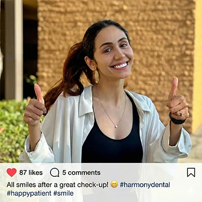 A happy, smiling patient standing outside the Harmony Dental Care clinic after a comfortable and successful dental visit